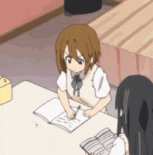 a girl is sitting at a table writing in a notebook .