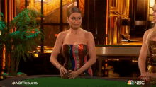 a woman in a strapless dress is standing at a poker table holding a card ..