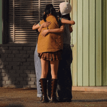 a woman in a plaid skirt is hugging another woman