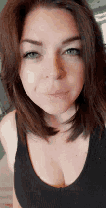 a close up of a woman 's face with a black tank top on .