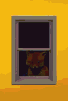 a cat is looking out of a window with a yellow wall in the background