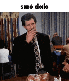 a man in a suit and tie is sitting at a table with a tray of bread and the word saro ciccio above him