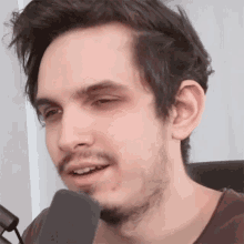 a man with a beard is talking into a microphone and making a funny face
