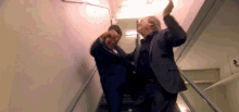 two men in suits are fighting in a hallway