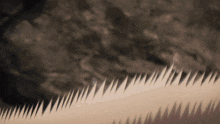 a close up of a saw blade with sharp teeth on a brown background