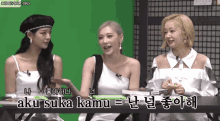 three women are sitting at a table with aku suka kamu written on the green screen