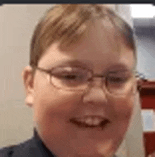 a close up of a young boy wearing glasses smiling .
