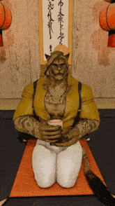 a man in a yellow shirt is kneeling down and holding a cup of tea