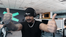 a man wearing headphones and a hat that says blizzard gives a thumbs up