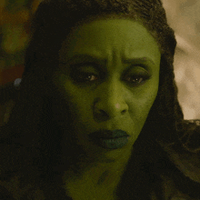 a woman with green paint on her face looks at the camera