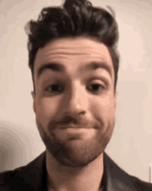 a man with a beard is making a funny face with his eyes closed .