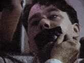 a man with duct tape on his mouth is being kissed by another man