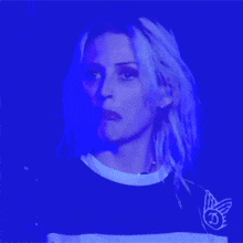 a woman in a black and white striped shirt is standing in front of a blue light