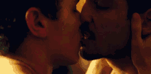 a man and a woman are kissing in a dark room in a close up of their faces .