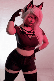a woman with pink hair and cat ears is wearing a black top