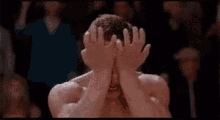 a man without a shirt is making a funny face with his mouth open in front of a crowd .