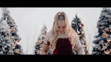 a young woman in a red dress is standing in front of a christmas tree .
