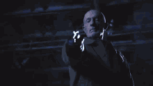 a bald man in a suit is holding a blue light in his hand .