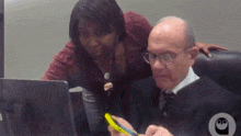 a man and a woman are looking at a laptop screen