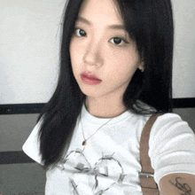 a woman wearing a white shirt with barbed wire on it taking a selfie