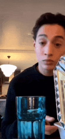 a young man is holding a blue glass and a picture frame