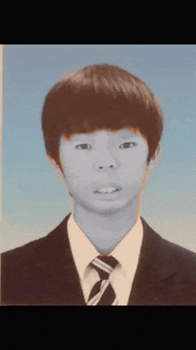 a young man in a suit and tie looks at the camera with a blue background