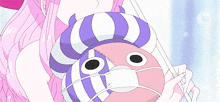 a girl with pink hair is holding a stuffed animal with a face mask on it