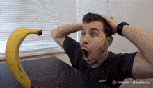 a man in a black shirt holds his hands to his head in front of a banana that says hailuo ai