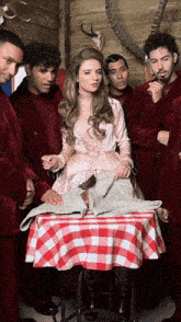 a woman in a pink dress stands in front of a table with a red and white checkered tablecloth