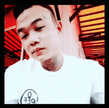 a man with a tattoo on his neck is wearing a white t-shirt with the letter o on it
