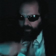 a man with a beard wearing sunglasses and a tie .
