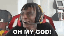 a man wearing headphones and a microphone is sitting in a chair and saying oh my god .