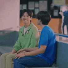 two young men are sitting next to each other and smiling