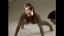 a man in a bodysuit is doing push ups with his mouth open