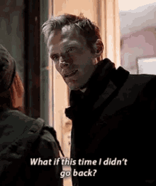 a man in a black coat is talking to a woman in a green jacket .