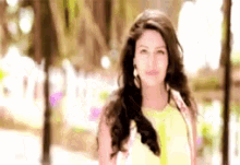 a woman in a yellow dress is walking down a street and smiling .