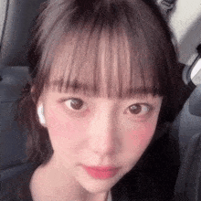 a close up of a woman 's face while sitting in a car with headphones on .