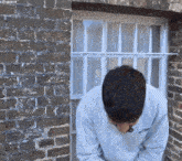 a man standing in front of a brick wall with a window behind him