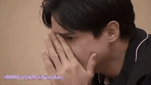 a man is covering his face with his hand .