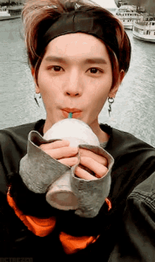 a man wearing a headband drinking from a cup with a straw