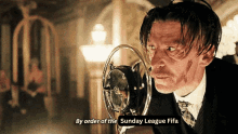 a man speaking into a microphone with the words by order of the sunday league fifa on the bottom