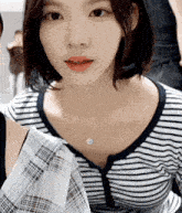a close up of a woman wearing a striped shirt and a plaid skirt