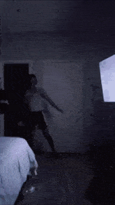 a person is dancing in a dark room in front of a television .