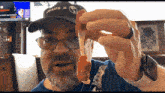 a man wearing a hat that says jesus holds up a piece of food