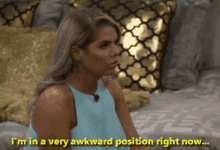 a woman is sitting on a bed saying i 'm in a very awkward position right now