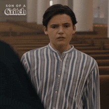 a young man in a striped shirt is standing in a church with the words son of a grifch behind him