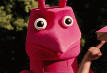 a person wearing a pink ant costume is holding a box
