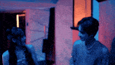 a man and a woman are standing next to each other in a room with blue lights