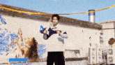 a man is standing in front of a wall with a painting of a woman holding a sword .