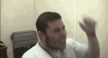 a man with a beard is making a funny face and waving his hand in the air .